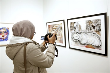 woman taking a photo of framed paintings