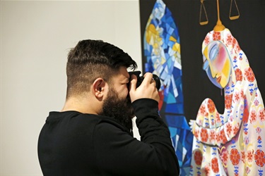 Young man taking a close-up photograph of a painting