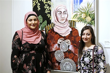 Two women posing on either side of a large painting