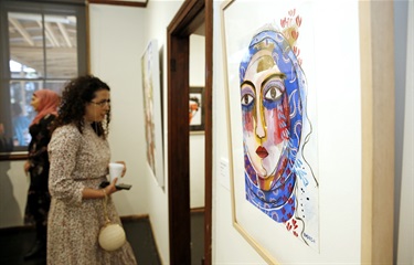 visitors looking at paintings on the wall of a gallery