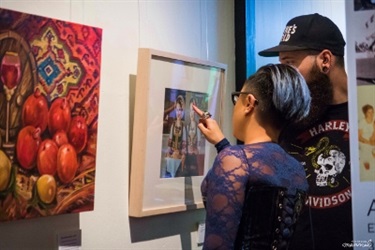 Two people looking and pointing at a framed collage of photographs