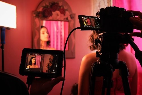 Cameras filming young woman looking at herself in a mirror