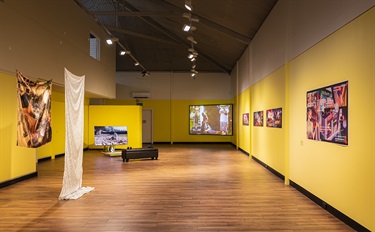Exhibition installation view of Here After showing multiple artworks in a yellow gallery space