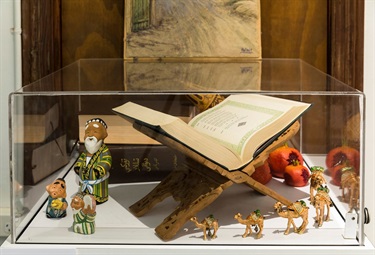 Display of traditional ornamental figures and a opened book on a stand