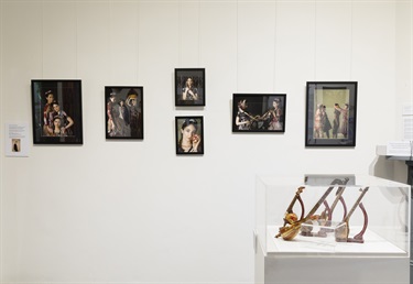 Photographs on museum wall and display of miniature musical instruments