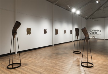 View of the gallery space with multiple copper sculptures on stands and on the wall
