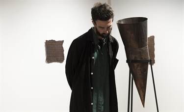 Male visitor listens closely to the sound coming out of a copper sculpture