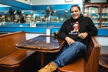 Portrait of a young man sitting at a diner table smiling at the camera