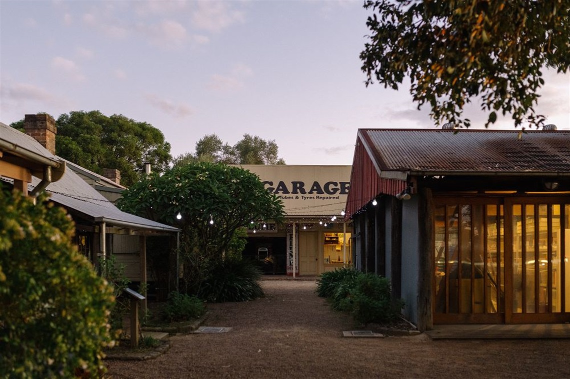 Photo of the Vintage Village at FCMG, lit up with fairy lights around sunset. 