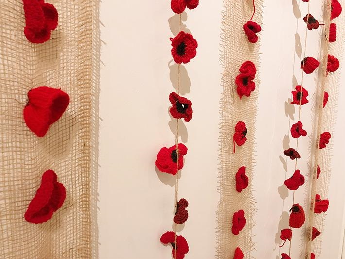 Fake poppies on strings and nets hung on a white wall