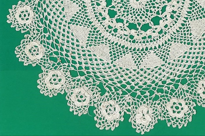 Handmade white doily against a green background by Linda Brescia