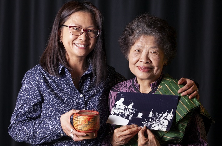 Photograph of Suzanne Sivieng with her mother Bounkeo Sivieng smiling and posing while holding their personal keepsakes