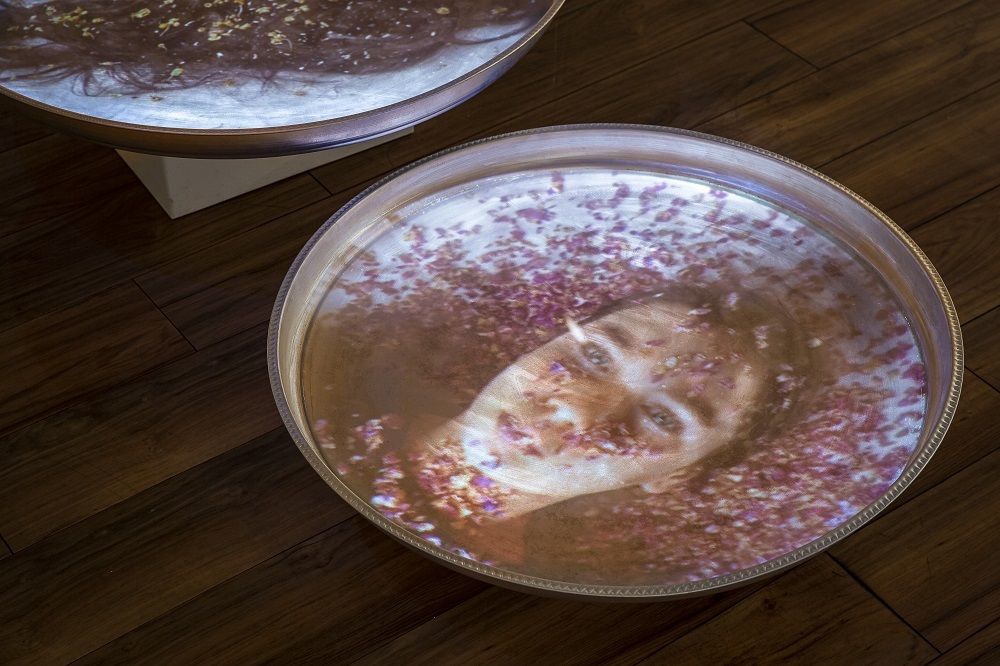 Image of a girl laying in rose petals projected on a metal tray 