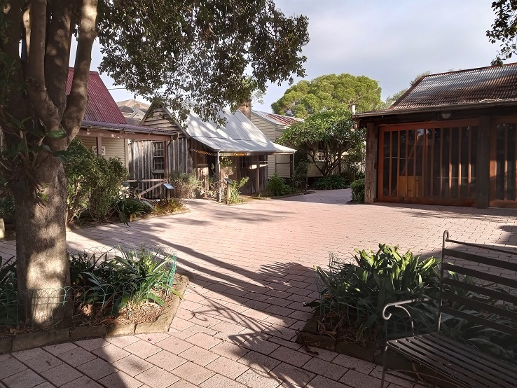 Photograph of the Vintage Village in sunlight with light red paving
